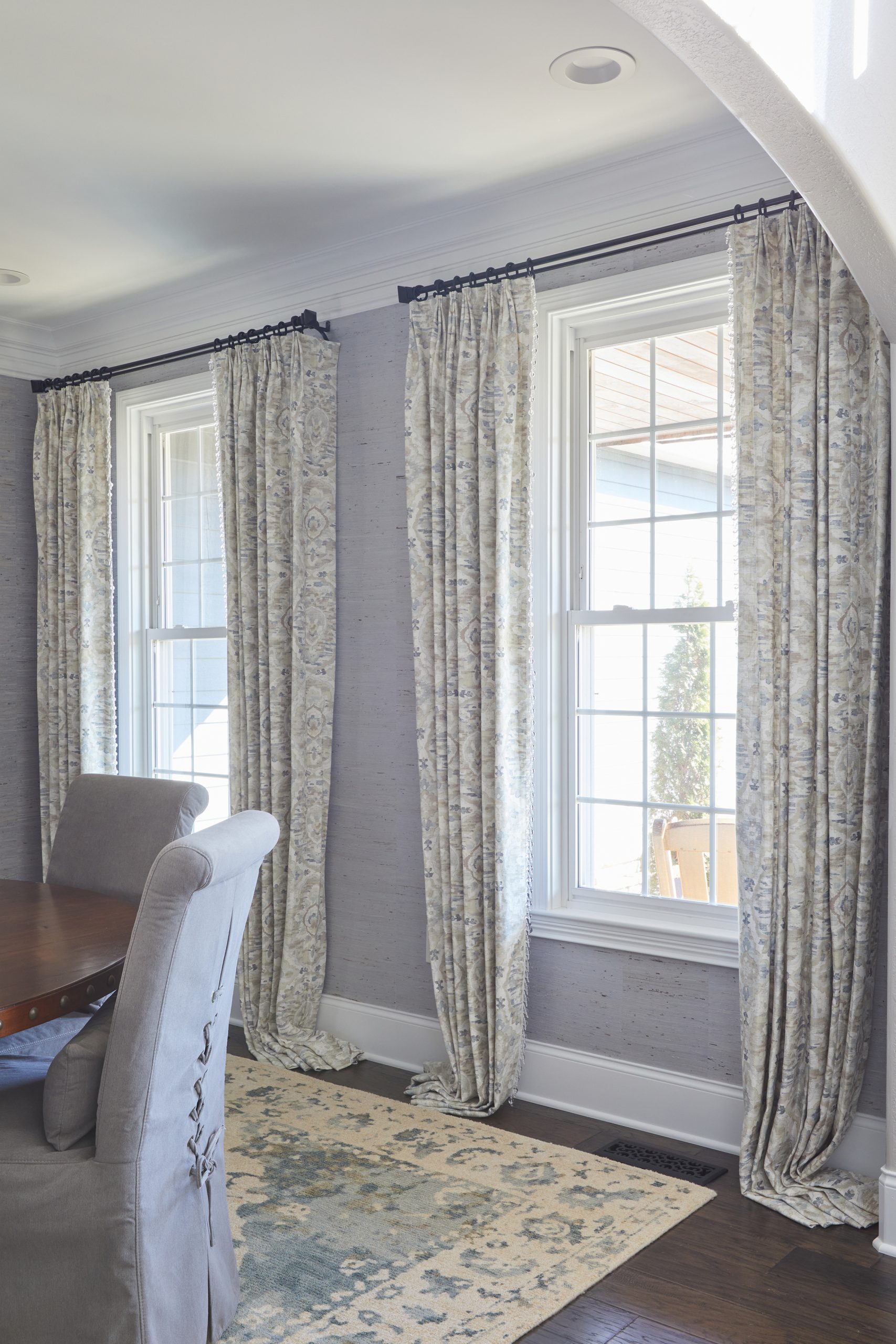 Elegant patterned drapes puddling gracefully on dark hardwood floors in a dining room
