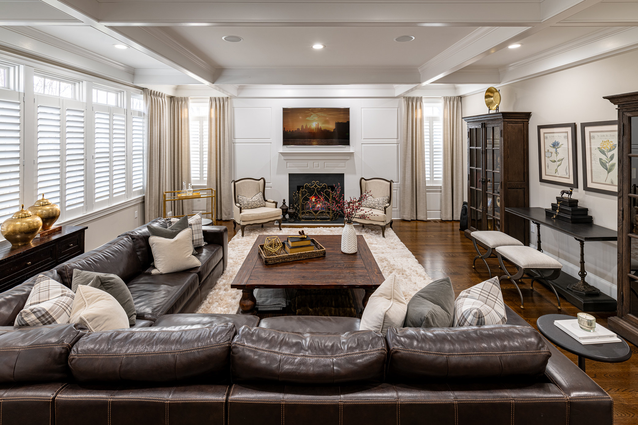 Traditional living room with brown leather sectional, coffered ceiling, and antique dark wood furniture