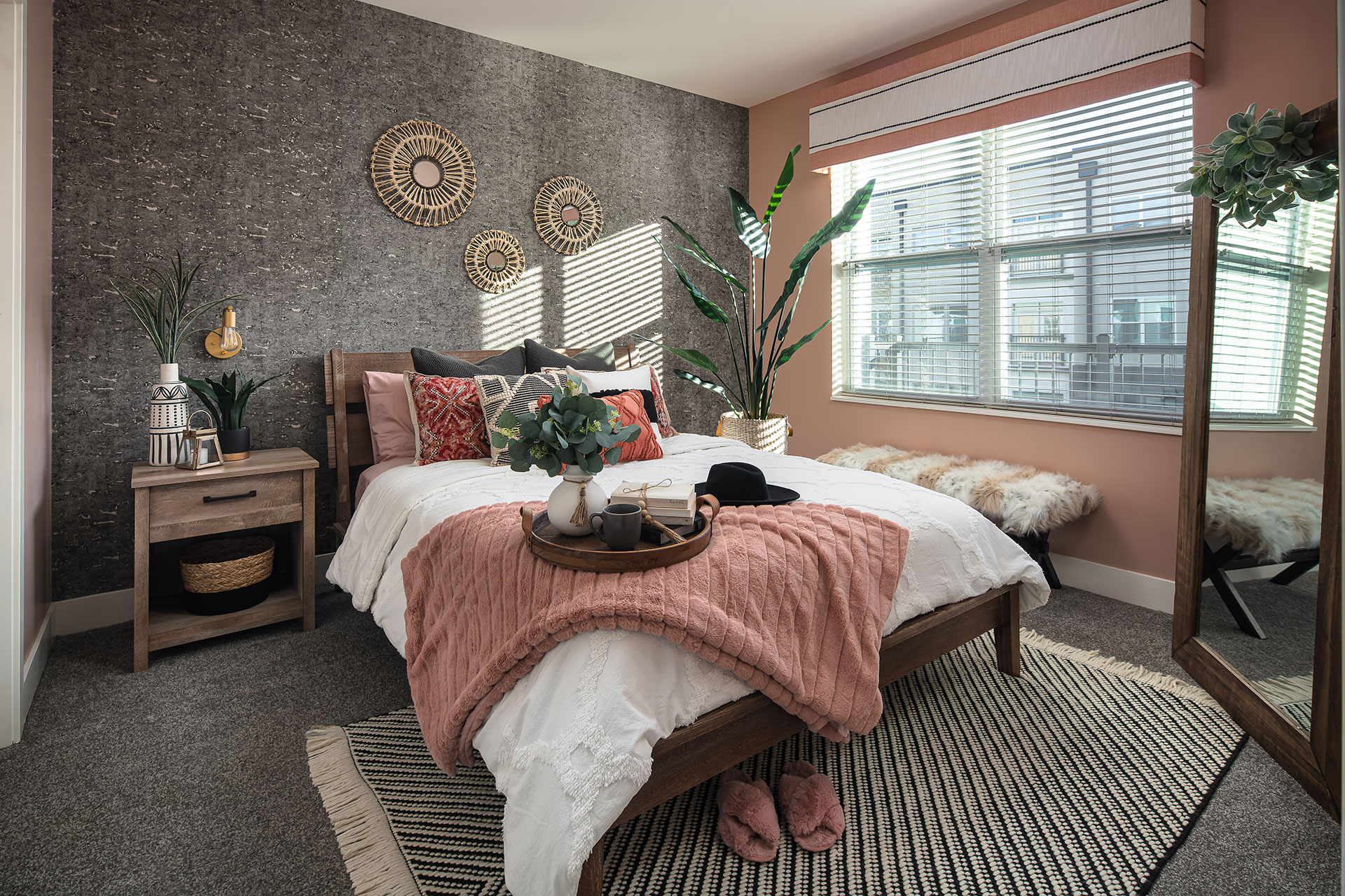 Boho-chic bedroom with cork accent wall, dusty rose accents and layered natural textures