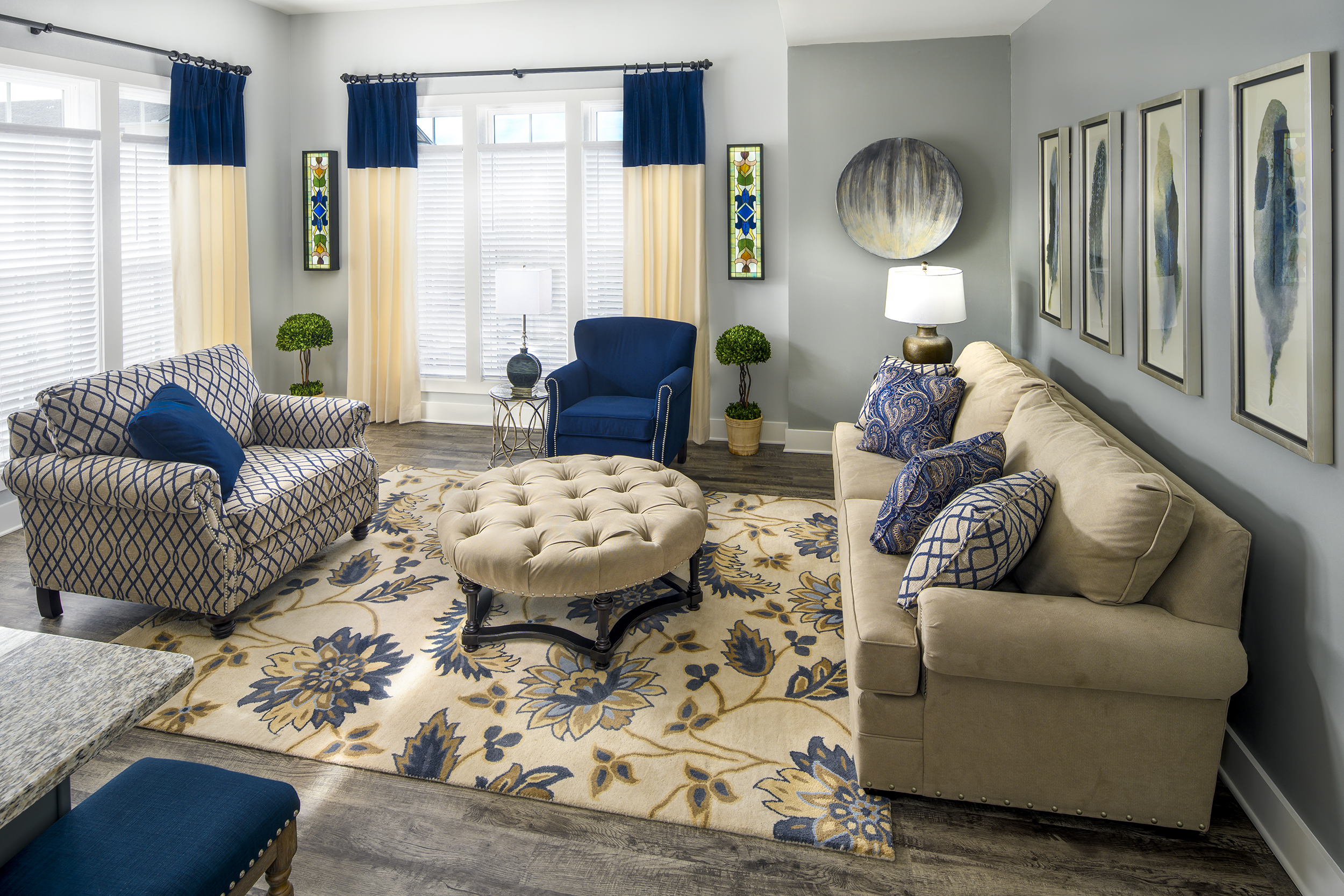 Traditional living room with navy floral rug, tufted ottoman, and coordinated upholstery patterns in cream and blue